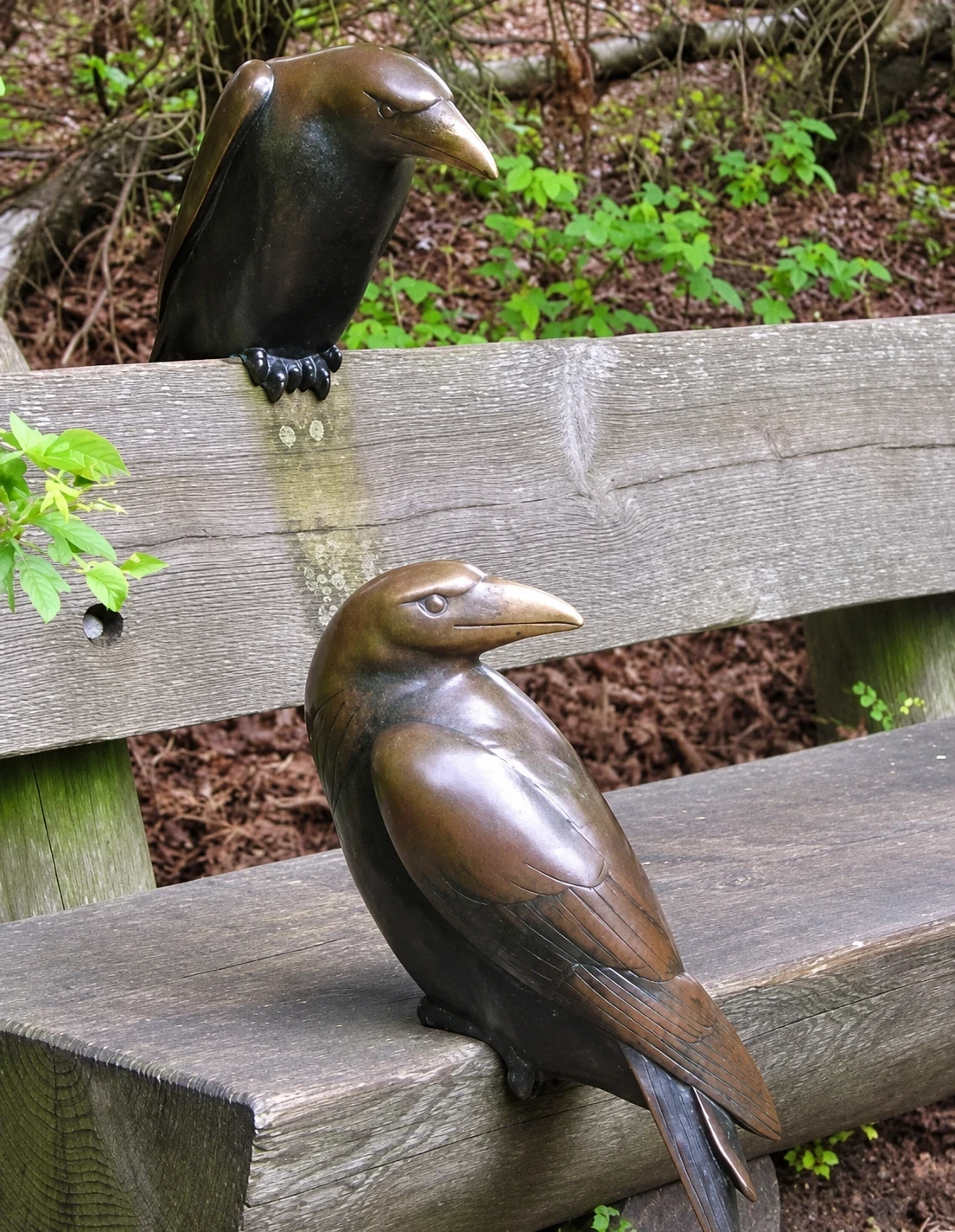 Dos esculturas de aves situadas junto a un banco en un jardín