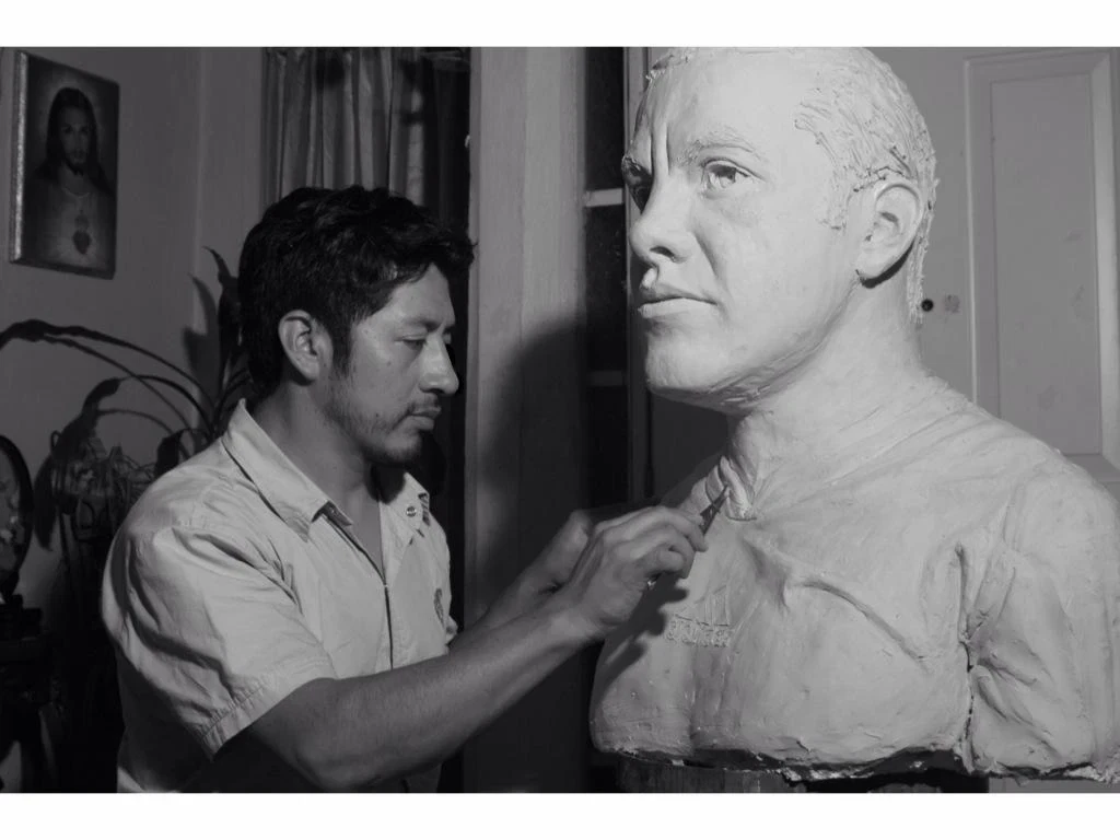 El escultor trabajando junto a un busto de gran formato