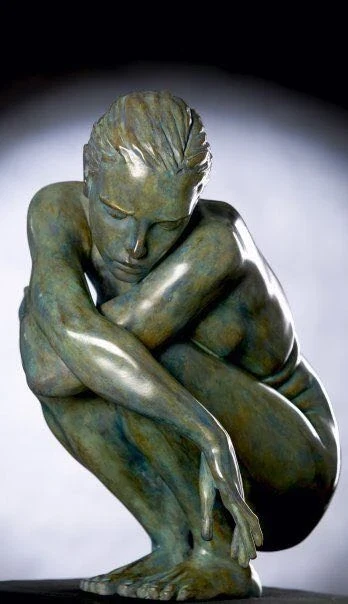 Escultura de una figura sentada con la cabeza inclinada y los brazos recogidos